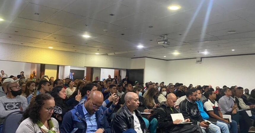 会議室に着席し、会議やセミナーに参加する多様な人々。