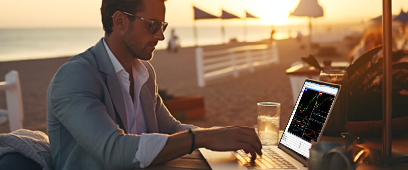 Un homme assis à une table, concentré sur son ordinateur portable, avec un arrière-plan neutre.
