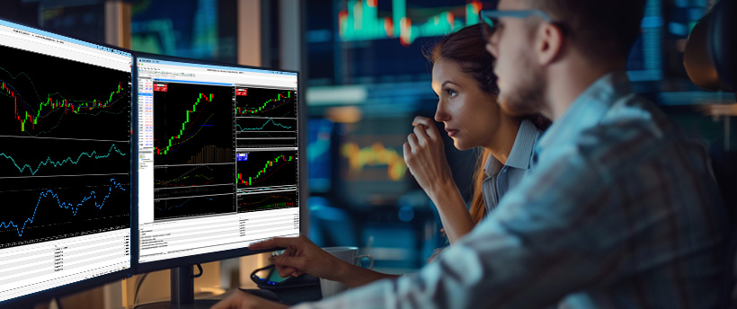 Dois traders de forex analisando dados de negociação em uma tela de computador, focando na psicologia do trading e nas tendências do mercado